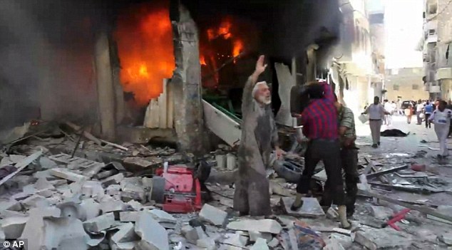 Horror: This picture shows the destruction in Aleppo following a devastating air strike by government forces. Syrian men throw buckets of water toward a burning building