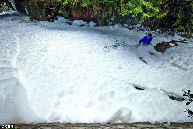 'Panic': A local man is dwarfed by the mass of suds floating down a river in southern China