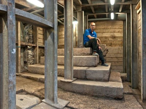 Joe Uziel, co-director of the excavation from the Israel Antiquities Authority, sitting atop the stepped structure from the Second Temple period. (Photo: Shai Halevy, courtesy Israel Antiquities Authority)