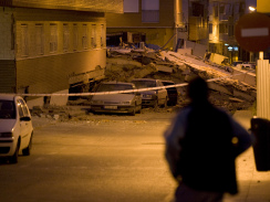 A man looks at cars crashed by debris from a collapsed building in Lorca, southern Spain, on May 11, 2011 after a magnitude 5.2 quake.